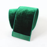 A roll of emerald green velvet ribbon or trim, shown on a clean white background.