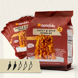 Momofuku Sweet & Spicy Noodles in a large red bag with several smaller single-serve packets fanned behind it. A small card at the bottom shows five pepper illustrations.