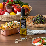 Olivelle black truffle oil bottle on a wooden table with food and vegetables in the background