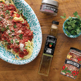 Spaghetti dish with olive oil and seasoning packets on a wooden table