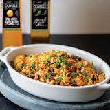 White dish of food with bottles of Olivelle olive oil in the background
