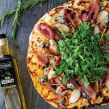 Pizza with prosciutto, arugula, and blue cheese on a wooden surface with a bottle of olive oil.