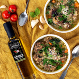 Two bowls of soup with a bottle of Olivelle Pizzaiolo olive oil on a yellow cloth.
