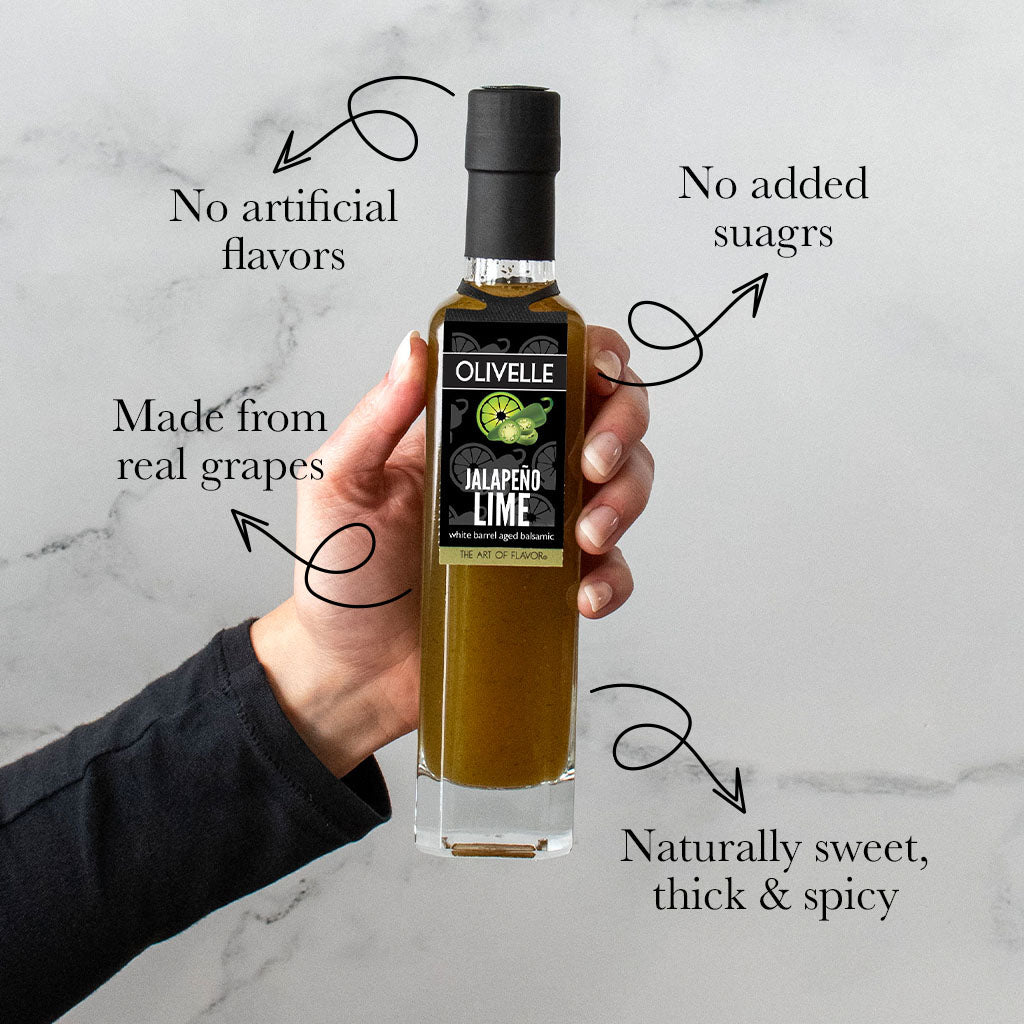 Bottle of Olivelle Jalapeno Lime product held by a hand on a marble background with text highlighting features.