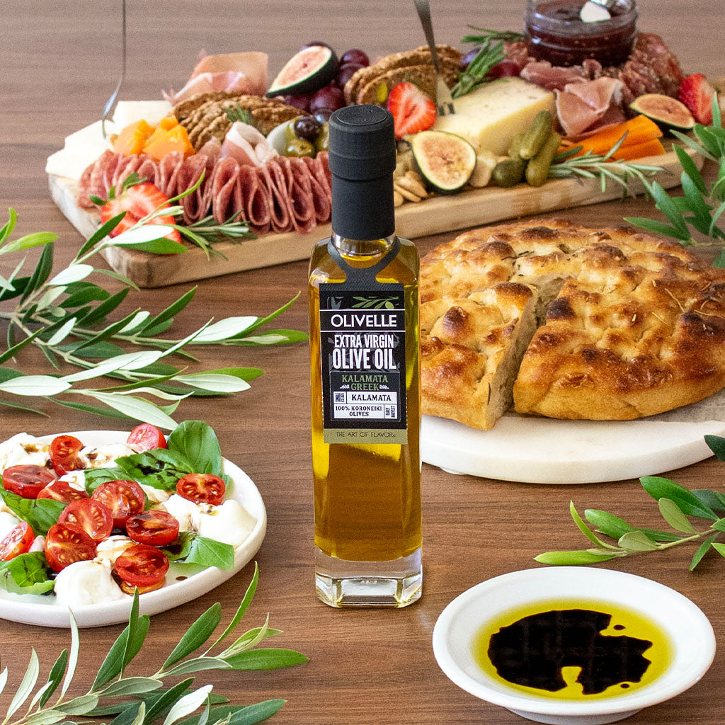 Olivelle olive oil bottle with a charcuterie board and bread on a wooden table.