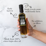 Hand holding a bottle of Olivelle olive oil with text highlighting its features on a marble background.