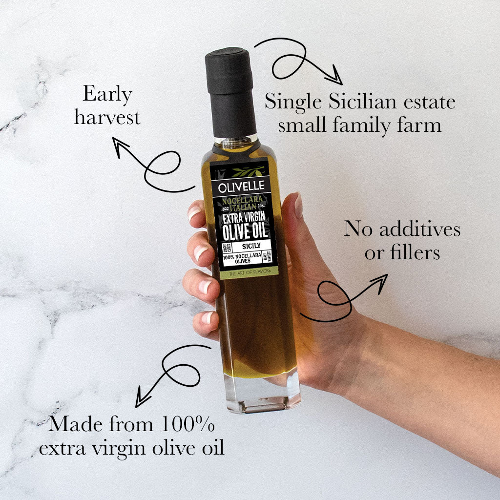Bottle of Olivelle olive oil held by a hand with text highlighting features on a marble background