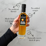 Hand holding a bottle of Olivelle Pineapple Habanero product with text on a marble background
