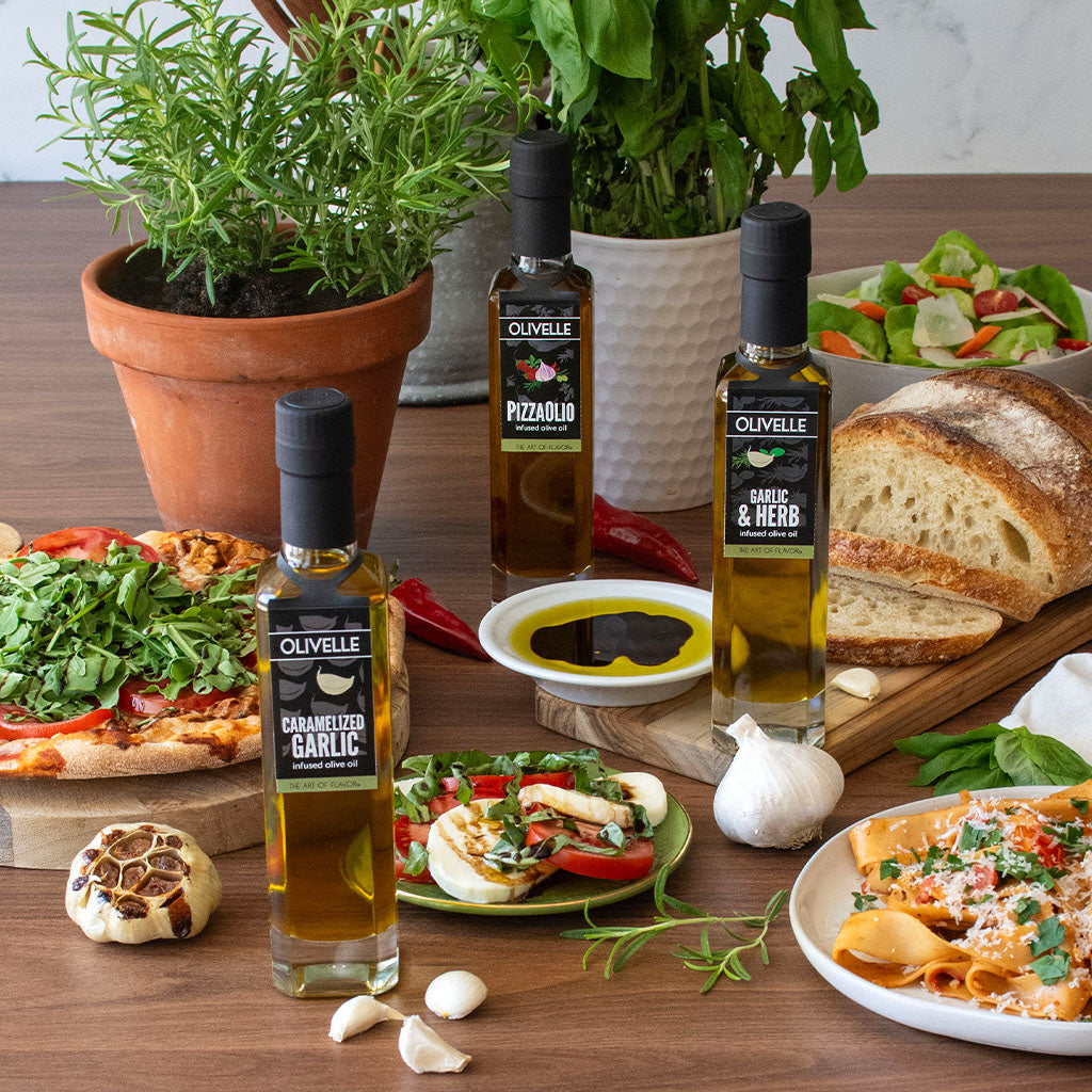 Table with olive oil bottles, bread, salad, and other food items on a wooden surface.