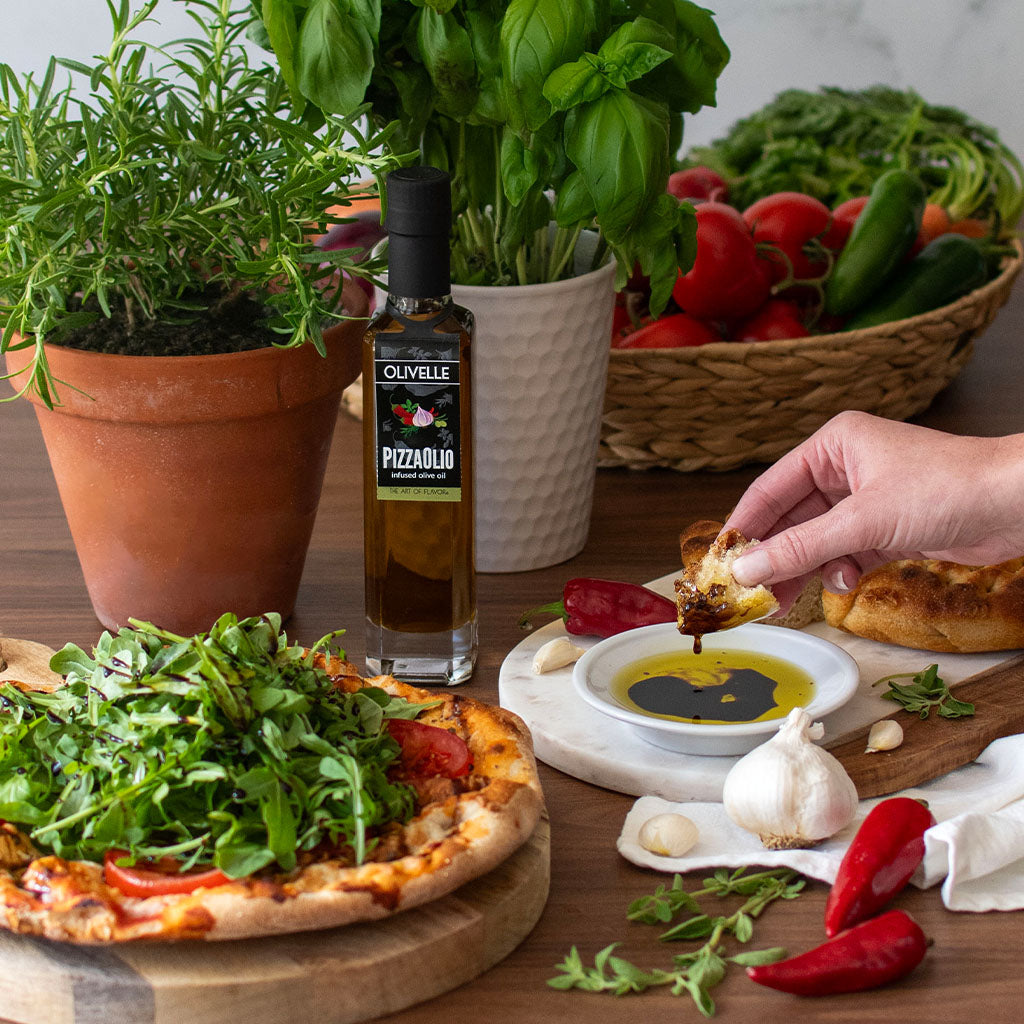 Olive oil bottle with a pizza and fresh ingredients on a table