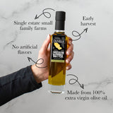 Hand holding a bottle of Olivelle olive oil with text highlighting features on a marble background