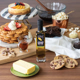 Table with desserts, a bottle of olive oil, and cookies on a wooden surface.