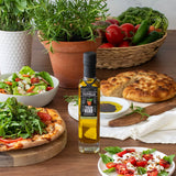 Olivelle Tuscan Herb oil bottle on a table with pizza, salad, and bread