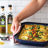 Person holding a tray of enchiladas with ingredients in the background