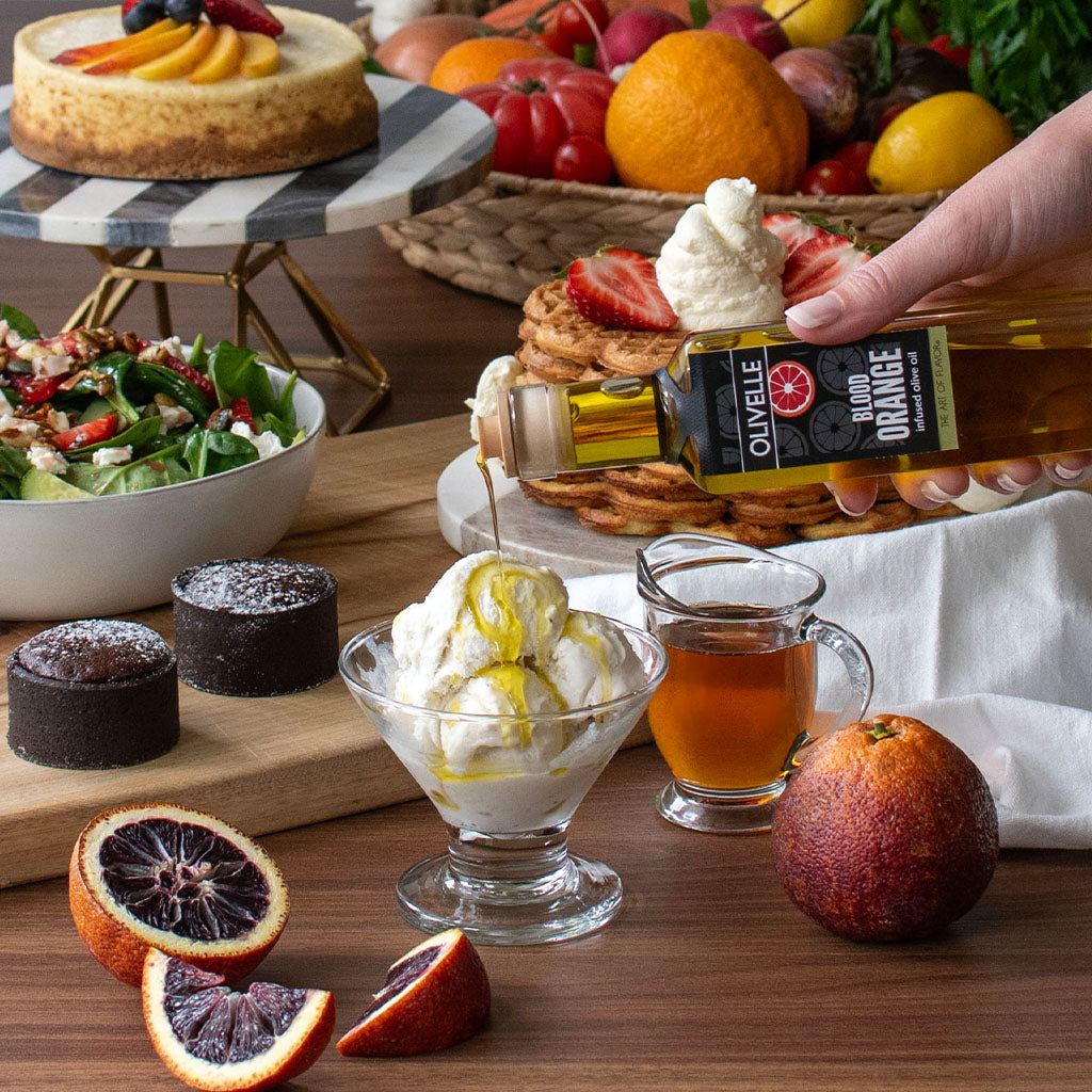 Table with various desserts, fruits, and a bottle of olive oil.