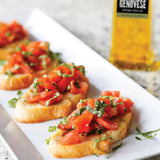 Bruschetta with tomatoes and basil on a white plate with a bottle of Genovese olive oil in the background.