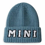 A blue ribbed knit beanie hat with a folded cuff featuring the word 'MINI' embroidered in white with black outlines across the front.