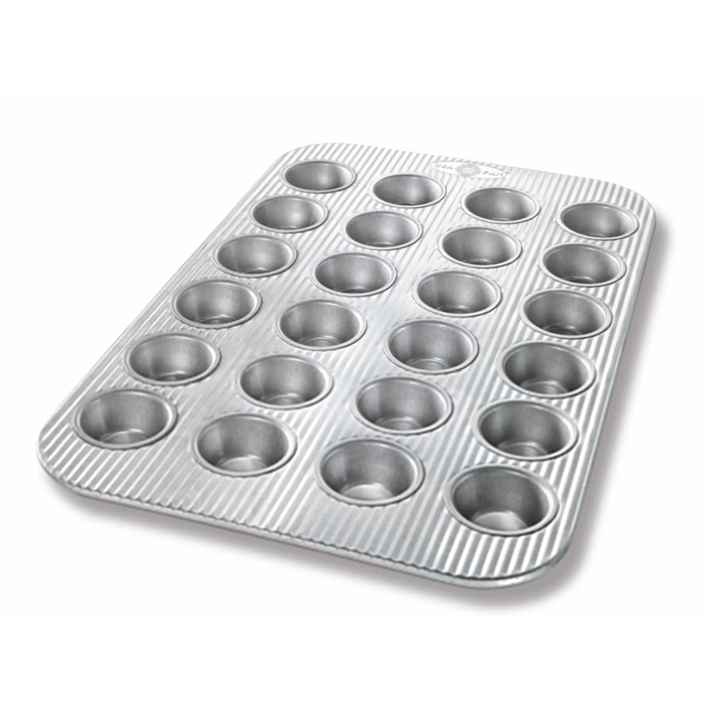 Metal muffin tin with 24 cups on a white background