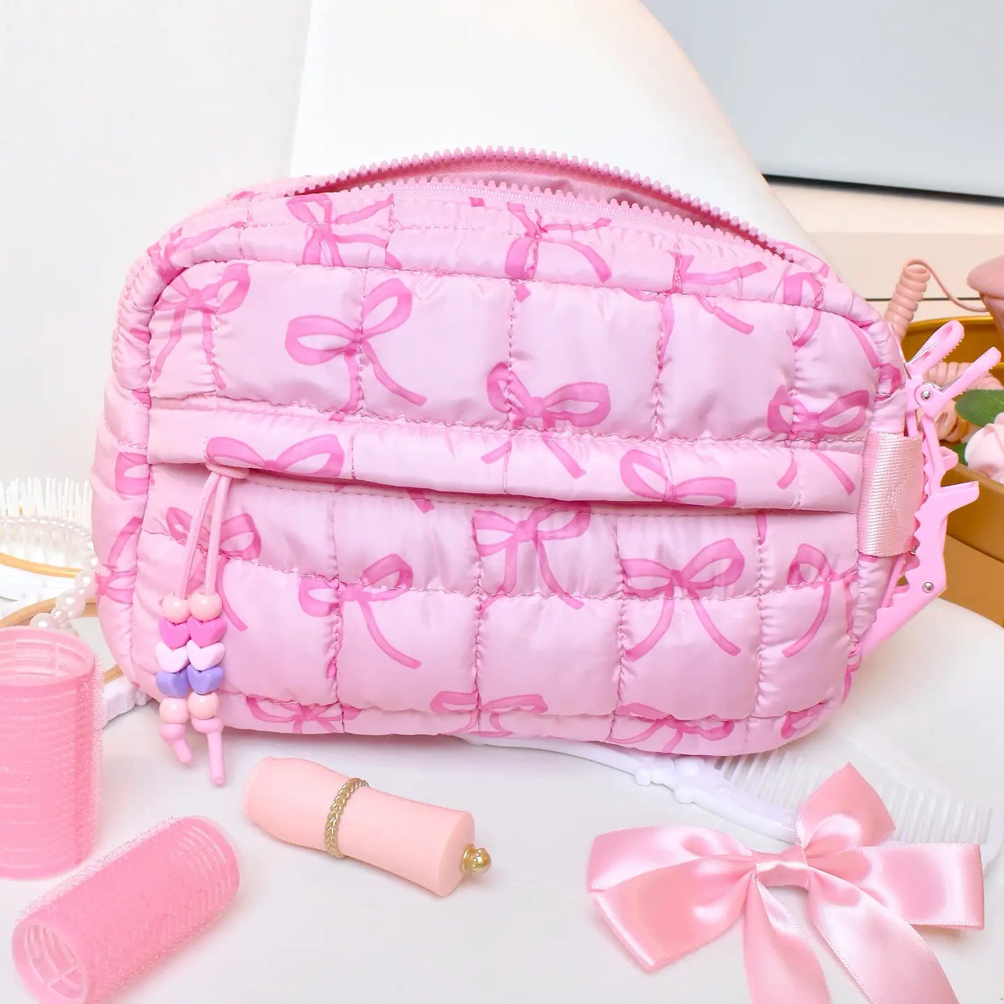 Pink cosmetic bag with bow pattern on a white surface