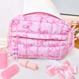 Pink cosmetic bag with bow pattern on a white surface