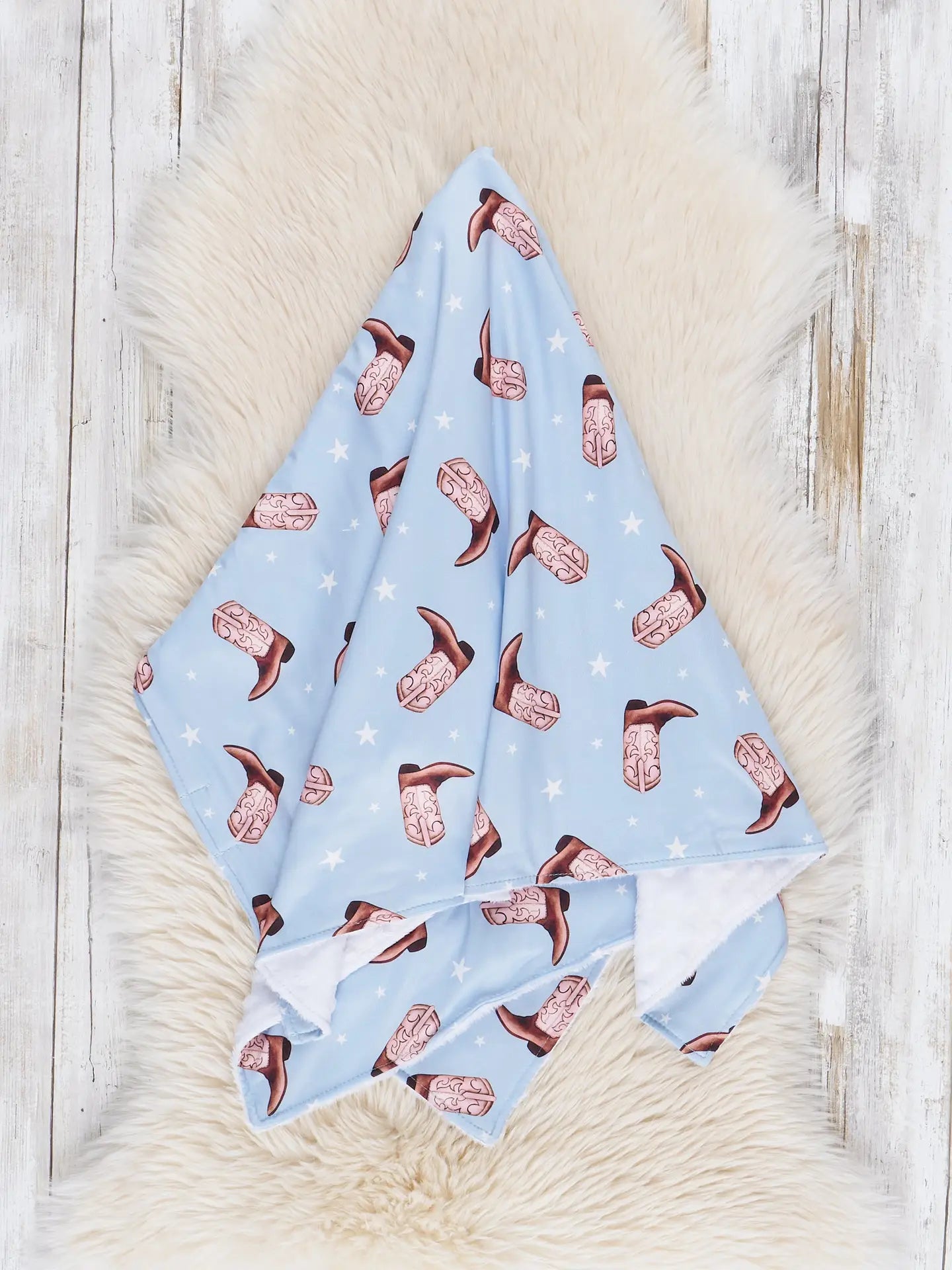 Baby blanket with cowboy boot pattern on a wooden surface