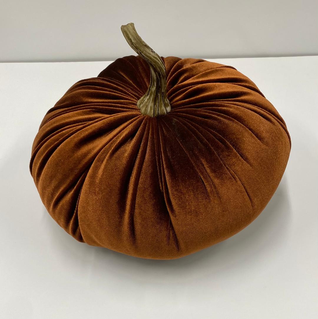 A decorative orange velvet pumpkin with a realistic stem on a white background.