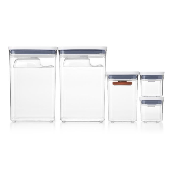 A set of three OXO baking essential pop containers in different sizes with a clear body and blue lids.