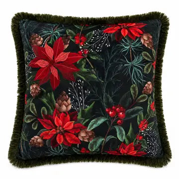 A square decorative throw pillow with a dark green fringed border and a festive floral tapestry pattern featuring red poinsettias, green leaves, pinecones, and berries on a black background.