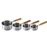 Set of four stainless steel measuring cups with wooden handles on a white background