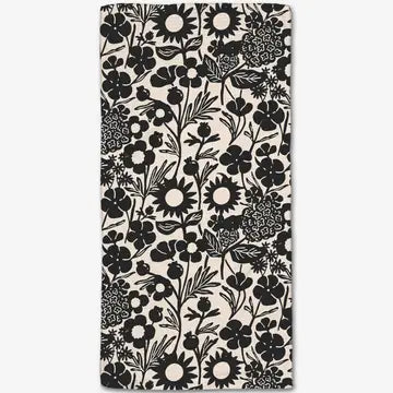 A rectangular fabric item, likely a towel or blanket, featuring a black and off-white floral pattern.