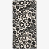 A rectangular fabric item, likely a towel or blanket, featuring a black and off-white floral pattern.