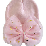 A light pink knit baby beanie featuring a large matching pink tulle bow decorated with gold and silver foil stars and crescent moons, shown on a plain white background.