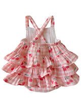 Pink tiered dress with cherry pattern on a white background