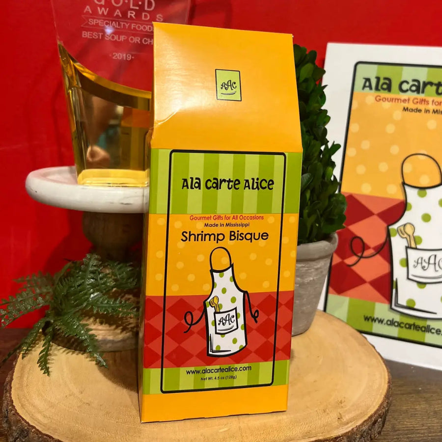 Ala Carte Alice Shrimp Bisque packaging on a wooden surface with a red background