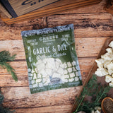 Packaged Garlic & Dill Cheese Curds on a wooden surface with herbs and a book.