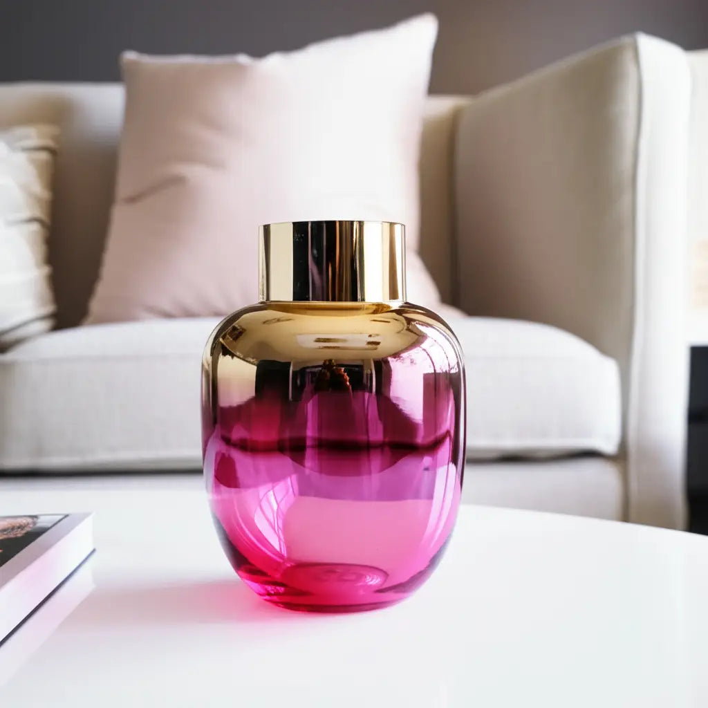 Pink and gold glass vase on a table with a blurred sofa in the background