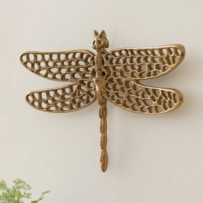 Decorative brass dragonfly wall art on a light background