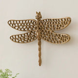 Decorative brass dragonfly wall art on a light background