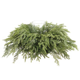 Green artificial wreath with a clear glass vase on a white background