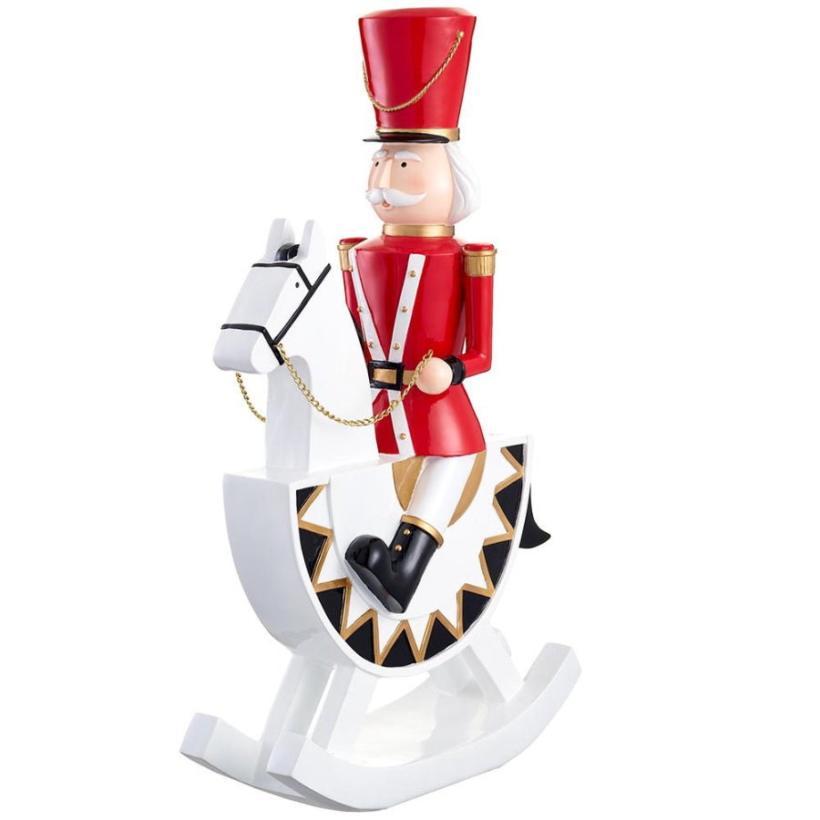 Decorative figure of a toy soldier on a rocking horse with a red hat and white outfit.