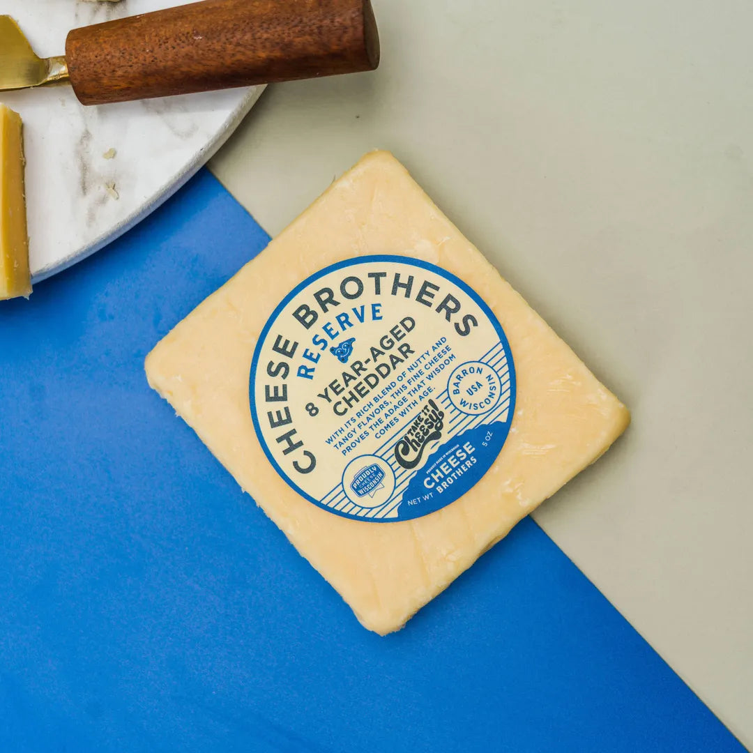 Block of cheese with a 'Cheese Brothers Reserve' label on a blue surface