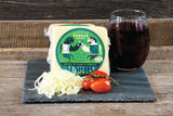 Cheese package with a glass of dark liquid on a wooden surface