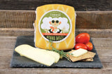 Block of mozzarella cheese with packaging labeled 'Nonna Mozzarella' on a slate board with vegetables and crackers.