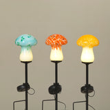 This image displays a set of three solar lighted glass mushrooms, each distinctively colored to enhance visual appeal. The mushrooms are designed with a translucent glass top, available in shades of blue, orange, and yellow, complemented by a solid black stem.