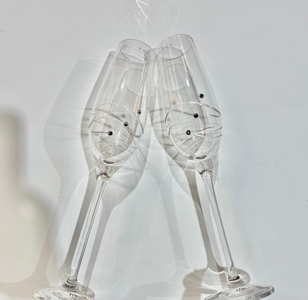 Two clear glass flute glasses with silver stems, positioned close together as if toasting.