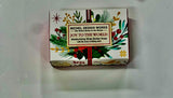 This image features a packaged bar of soap, specifically from Michel Design Works. The bar is contained within a brightly colored box that is decorated with a festive, Christmas-themed design, including holly and other holiday greens.