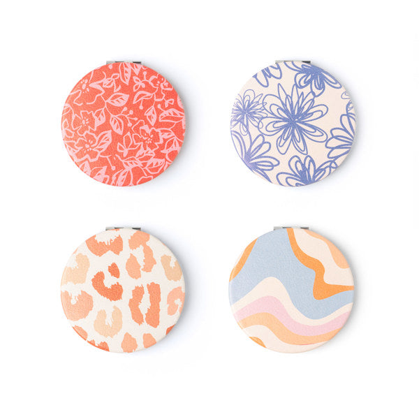 Four compact mirrors with different patterns on the covers, displayed side by side.