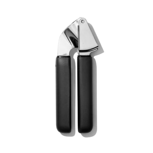 A stainless steel and black silicone OXO garlic press.