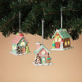 Three lighted clay dough house ornaments with pastel colors and festive decorations, hanging from a Christmas tree.