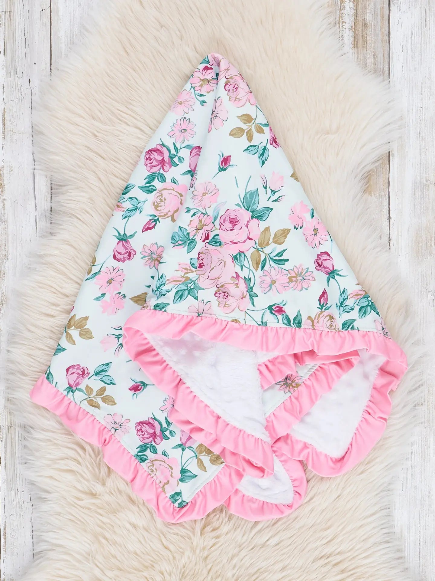 Floral baby blanket with ruffle edge on a soft surface